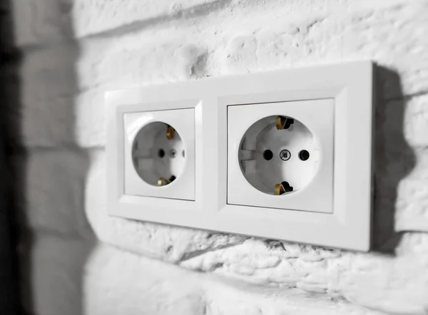 Plastic German double socket-outlets type F with grounding. Pair of empty, unplugged, european white power sockets or electrical outlets CEE 7 with two earthing clips against brick wall. — стоковое фото
