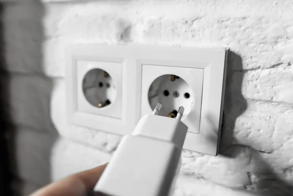 Unplugging idle appliances saves electricity. Idle phone chargers or power adapters. Vampire power, standby power. Plug-in adapter into european wall outlet. USB plug insert into electric wall socket — стоковое фото