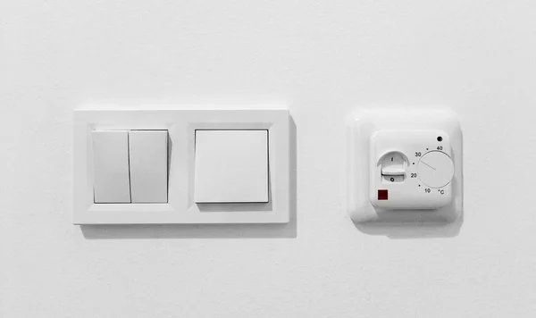 Paar einfache Lichtschalter mit Dimmer. Preiswerter mechanischer Kunststoff-Doppelschalter mit Thermostat gegen weiße Wand. Altes Bedienfeld für Klimaanlagen. Smart Home Geräte zur Klimaregelung — Stockfoto