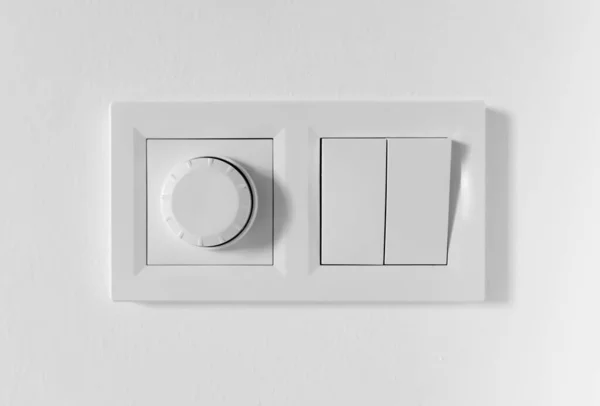 Pair of simple light switches with dimmer. Inexpensive plastic mechanical double switch with thermostat against white wall. Old air conditioner control panel. Smart Home Climate Control Appliances — Stock Photo, Image