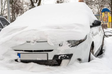 Kar fırtınasından sonra şehir caddesi. Kar ve buzun altında sıkışmış arabalar. Gömülü araç yolda kar yığınında. Yoğun kar yağışından sonra kışın otopark. Temizlenmemiş yollar. Rekor miktarda kar yağıyor..