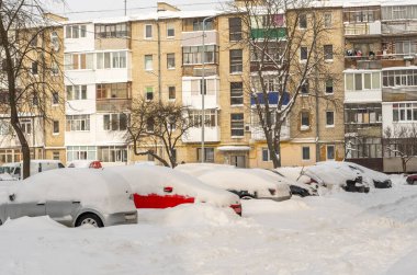 Kar fırtınasından sonra şehir caddesi. Kar ve buzun altında sıkışmış arabalar. Gömülü araç yolda kar yığınında. Yoğun kar yağışından sonra kışın otopark. Temizlenmemiş yollar. Rekor miktarda kar yağıyor..