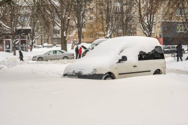 Lutsk, Ukrayna - 12 Şubat 2020: Kar ve buzda sıkışmış araba. Kar fırtınasından sonra şehir caddesi. Gömülü araç kar yığınında. Kışın kar yağdıktan sonra park etmek. Temizlenmemiş yol. Rekor miktarda kar yağıyor.