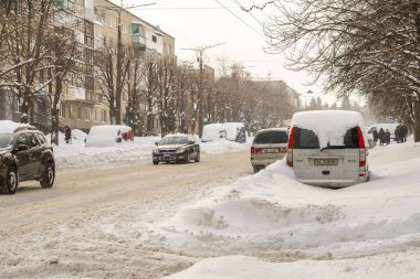 Lutsk, Ukrayna - 12 Şubat 2020: Kar ve buzda sıkışmış araba. Kar fırtınasından sonra şehir caddesi. Gömülü araç kar yığınında. Kışın kar yağdıktan sonra park etmek. Temizlenmemiş yol. Rekor miktarda kar yağıyor.