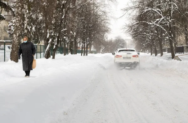 Lutsk, Ukrayna - 12 Şubat 2020: Kar fırtınasından sonra sokaktaki insanlar. Kar fırtınasından sonra şehir caddesi. Rekor miktarda kar yağıyor. Temizlenmemiş kaygan yollar ve kışın kaldırım. Kar yağışı içindeki arabalar