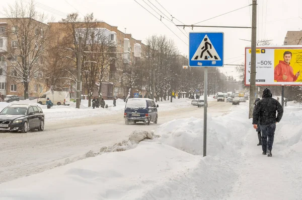 Lutsk, Ukrayna - 12 Şubat 2020: Kar fırtınasından sonra sokaktaki insanlar. Kar fırtınasından sonra şehir caddesi. Rekor miktarda kar yağıyor. Temizlenmemiş kaygan yollar ve kışın kaldırım. Kar yağışı içindeki arabalar