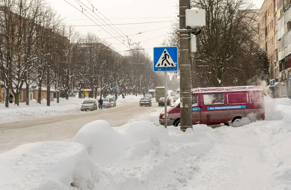 Lutsk, Ukrayna - 12 Şubat 2020: Kar fırtınasından sonra sokaktaki insanlar. Kar fırtınasından sonra şehir caddesi. Rekor miktarda kar yağıyor. Temizlenmemiş kaygan yollar ve kışın kaldırım. Kar yağışı içindeki arabalar