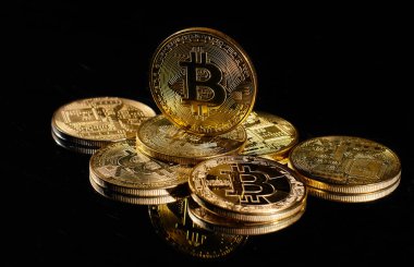 Bitcoin logolu yakın plan altın sikke. Şifreli para birimi Bitcoin BTC 'nin lideri siyah ayna yüzeyine karşı bozuk paraların tepesinde. Merkezi olmayan bir yığın dijital para birimi. Şifreli ödeme. Elektronik para.