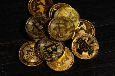 Siyah ahşap yüzeye karşı paraların tepesinde şifreli bitcoin BTC lideri. Bitcoin logolu yakın plan altın sikke. Merkezi olmayan dijital para birimleri yığını. Şifreli ödeme. Elektronik para