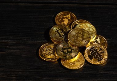 Siyah ahşap yüzeye karşı paraların tepesinde şifreli bitcoin BTC lideri. Bitcoin logolu yakın plan altın sikke. Merkezi olmayan dijital para birimleri yığını. Şifreli ödeme. Elektronik para