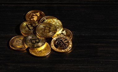 Siyah ahşap yüzeye karşı paraların tepesinde şifreli bitcoin BTC lideri. Bitcoin logolu yakın plan altın sikke. Merkezi olmayan dijital para birimleri yığını. Şifreli ödeme. Elektronik para