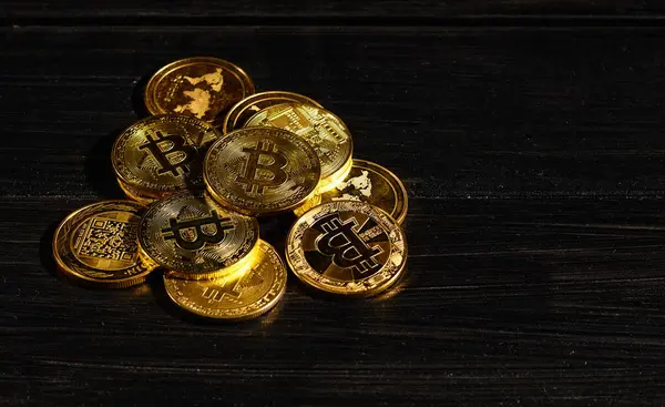 Siyah ahşap yüzeye karşı paraların tepesinde şifreli bitcoin BTC lideri. Bitcoin logolu yakın plan altın sikke. Merkezi olmayan dijital para birimleri yığını. Şifreli ödeme. Elektronik para
