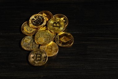 Siyah ahşap yüzeye karşı paraların tepesinde şifreli bitcoin BTC lideri. Bitcoin logolu yakın plan altın sikke. Merkezi olmayan dijital para birimleri yığını. Şifreli ödeme. Elektronik para