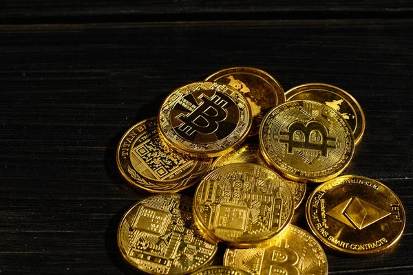 Siyah ahşap yüzeye karşı paraların tepesinde şifreli bitcoin BTC lideri. Bitcoin logolu yakın plan altın sikke. Merkezi olmayan dijital para birimleri yığını. Şifreli ödeme. Elektronik para