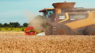 Lutsk, Ukrayna - 29 Temmuz 2020: Tahıl başlıklı hasat makinesi, tahıl gevreği toplayan geniş saman yayıcısı. Döner saman yürüteci buğday buğdayını keser ve harcar. Tarımsal makinelerle mahsul toplama