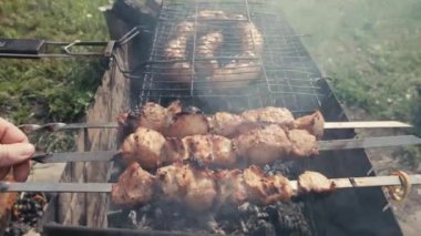 Barbekü et ve sosis ya da arka bahçede ızgarada ızgara sosis. Şiş kebap hazırlayan ya da kömürün üstüne şiş kebap yapan adam. Dışarıdaki metal şişte ızgara et. Mangal partisi ya da piknik yemeği. Yakın çekim.