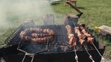 Barbekü et ve sosis ya da arka bahçede ızgarada ızgara sosis. Şiş kebap hazırlayan ya da kömürün üstüne şiş kebap yapan adam. Dışarıdaki metal şişte ızgara et. Mangal partisi ya da piknik yemeği. Yakın çekim.