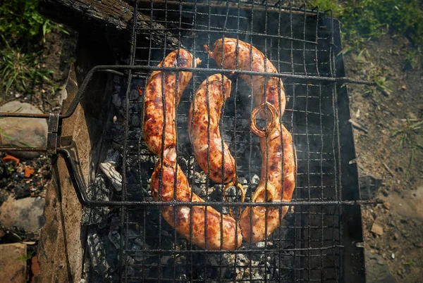 Carne de barbacoa y salchichas o salchichas en una parrilla en el patio trasero. Hombre preparando shashlik o shish kebab sobre carbón vegetal. Carne a la parrilla en pincho de metal al aire libre. Fiesta de barbacoa o picnic. Primer plano. —  Fotos de Stock