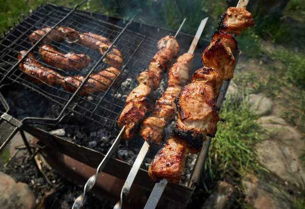 Κρέας μπάρμπεκιου και λουκάνικα ή λουκάνικα σε σχάρα στην πίσω αυλή. Ο άνθρωπος ετοιμάζει shashlik ή shish κεμπάπ πάνω από κάρβουνο. Ψητό κρέας σε μεταλλικό σουβλάκι. Μπάρμπεκιου κόμμα ή πικ-νικ φαγητό. Κοντινό πλάνο — Φωτογραφία Αρχείου