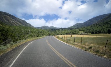 Utah 'taki Uinta Ulusal Ormanı' nda sıcak bir yaz gününde yol bulutlu.