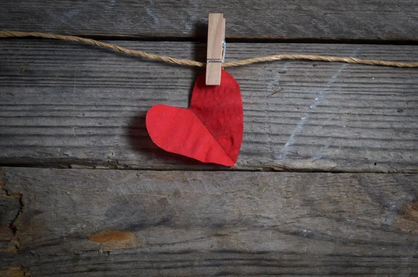 Red heart hanging on the clothesline. On old wood background. — Stock Photo, Image