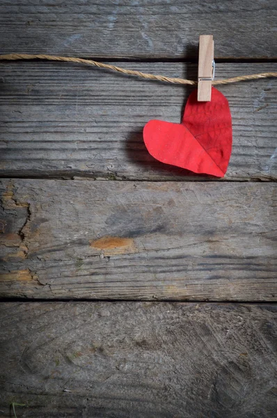 Red heart hanging on the clothesline. On old wood background. — Stock Photo, Image