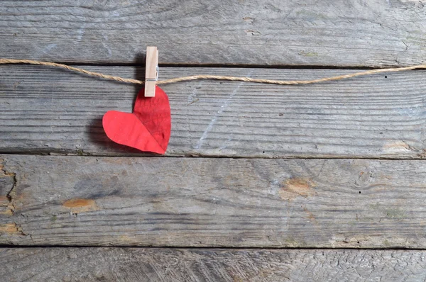 Red heart hanging on the clothesline. On old wood background. — Stock Photo, Image