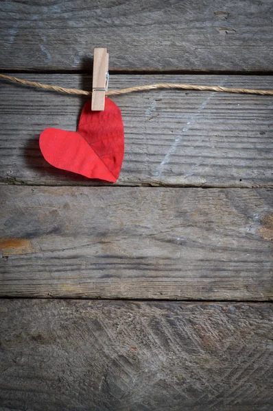 Červené srdce visí na prádelní šňůru. Na staré dřevěné pozadí. — Stock fotografie