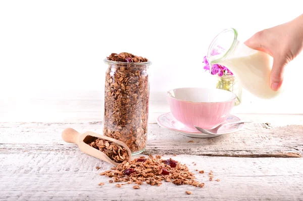 Homemade granola in open glass jar on white wooden background — Stock Photo, Image