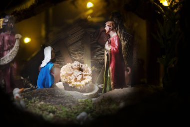 Noel İsa Mesih, Meryem ve Yusuf adına. Arkaplanda tahta heykelcikler.