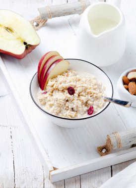 Kırsal beyaz ahşap tepside kırmızı elmalı yulaf ezmesi..