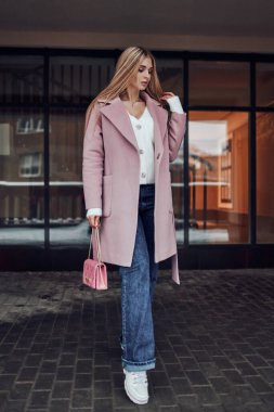 Binanın arka planında poz veren şık sarışın kız. Resim oturumu.