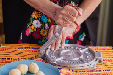 Meksika usulü el yapımı tortilla: Geleneksel kıyafetleri olan kadın Meksika 'da tortilla presi yapıyor.