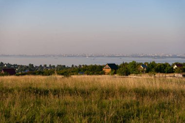 Köy, şehir, nehirde yüzen mavnalar.