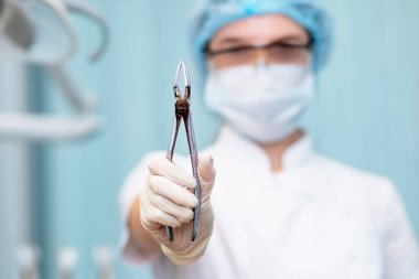 Diş çıkarma kıskaçları dişçi doktorunun ellerinde..