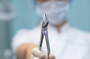 Diş çıkarma kıskaçları dişçi doktorunun ellerinde..