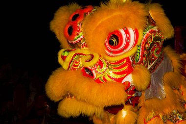 Asian New Year, traditional holiday. Street performances and dancing of a dragon and a lion. The head of a beautiful dragon at night against a background of black sky and fireworks.