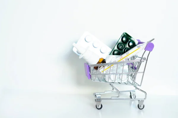 Tablets in a trolley on a white background, copy space. Basket, home delivery of medicines. home first aid kit for colds, diseases, viruses, epidemics. online purchase of medicines. — Stock Photo, Image