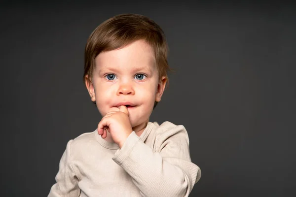 Serious little girl surprised, lost. The emotion of fear in the tears of a baby. child in on a solid solid background in the studio.