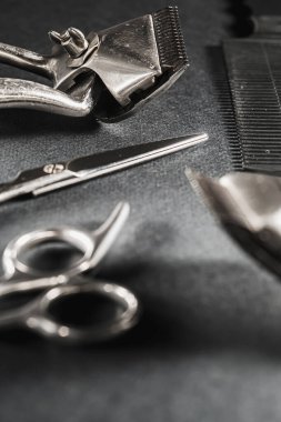 Siyah bir yüzeyde eski berber aletleri vardır. Klasik manuel saç makası, tarak, jilet, kuaför makası. siyah monokrom. Yakın plan. Berber dükkanı geçmişi. farklı gölgeler. düşey yönelim