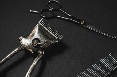 Siyah bir yüzeyde eski berber aletleri vardır. Klasik manuel saç makası, tarak, kuaför makası. siyah monokrom. Siyah arka plan. farklı gölgeler. yatay.