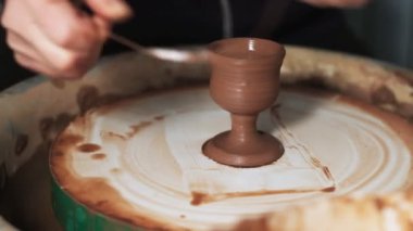 Eller çömlekçi çarkında çalışıyor. Potter çömlekçinin çarkındaki çömlek aletleriyle kil ürünü şekillendiriyor, el işi fabrikası özgün. Kapatın. 4k