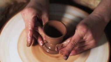 Eller çömlekçi çarkında çalışıyor. Potter çömlekçinin çarkındaki çömlek aletleriyle kil ürünü şekillendiriyor, el işi fabrikası özgün. Kapatın. 4k