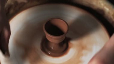 Eller çömlekçi çarkında çalışıyor. Potter çömlekçinin çarkındaki çömlek aletleriyle kil ürünü şekillendiriyor, el işi fabrikası özgün. Kapatın. 4k