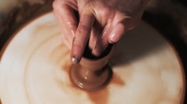 Eller çömlekçi çarkında çalışıyor. Potter çömlekçinin çarkındaki çömlek aletleriyle kil ürünü şekillendiriyor, el işi fabrikası özgün. Kapatın. 4k