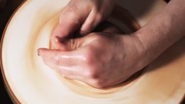 Eller çömlekçi çarkında çalışıyor. Potter çömlekçinin çarkındaki çömlek aletleriyle kil ürünü şekillendiriyor, el işi fabrikası özgün. Kapatın. 4k