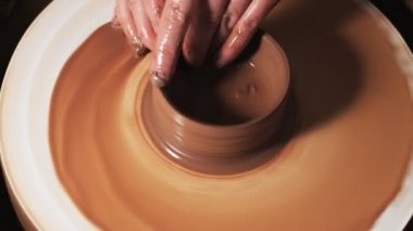 Eller çömlekçi çarkında çalışıyor. Potter çömlekçinin çarkındaki çömlek aletleriyle kil ürünü şekillendiriyor, el işi fabrikası özgün. Kapatın. 4k