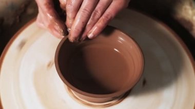 Eller çömlekçi çarkında çalışıyor. Potter çömlekçinin çarkındaki çömlek aletleriyle kil ürünü şekillendiriyor, el işi fabrikası özgün. Kapatın. 4k