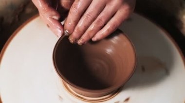 Eller çömlekçi çarkında çalışıyor. Potter çömlekçinin çarkındaki çömlek aletleriyle kil ürünü şekillendiriyor, el işi fabrikası özgün. Kapatın. 4k