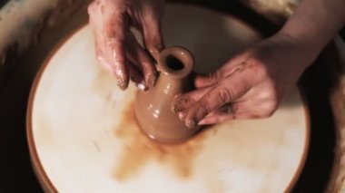 Eller çömlekçi çarkında çalışıyor. Potter çömlekçinin çarkındaki çömlek aletleriyle kil ürünü şekillendiriyor, el işi fabrikası özgün. Kapatın. 4k